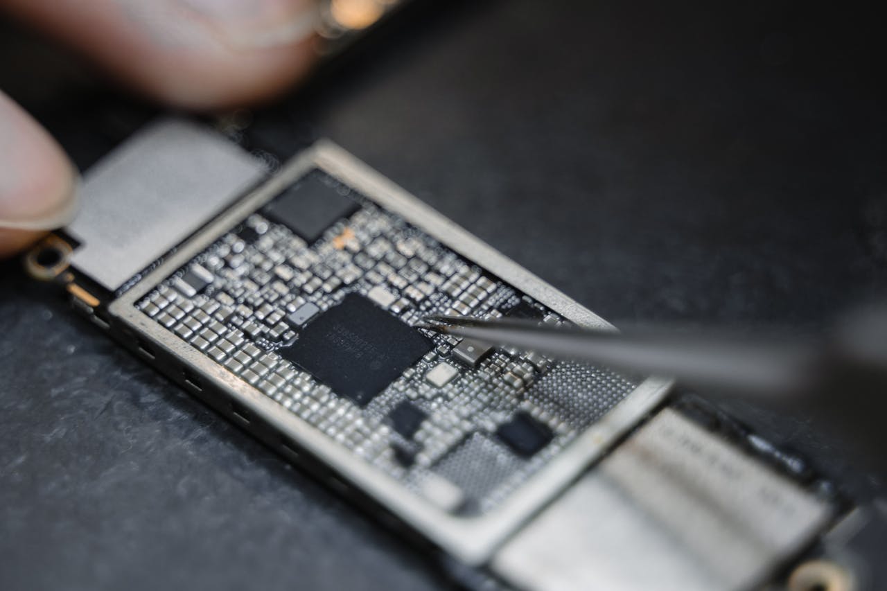 Services-03 Detailed view of a technician using tweezers to fix an electronic circuit board.